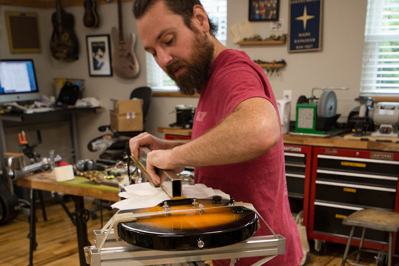 Man leveling frets with Fret/Fingerboard Leveler in Neck Jig